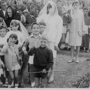 1964-65: Procesión del día del Corpus.  1ª fila: Meli, Consuelo, David/ 2ª fila: Gloria (detrás de ella: Julita (hija de Paulina) y detrás: Carmen (Segoviana), Ceci, Conchi, Magdalena (con velo), Mari (con velo), Javier, Mariano (detrás)/ Mujeres con los palos: Sra. Braulia -detrás: María (Feliciano) y Luis-, Daniela, Juanita, Santiaguín (monaguillo)/ fondo: María Cuenca y Pili (mantilla negra). ¿Jose? y ?.